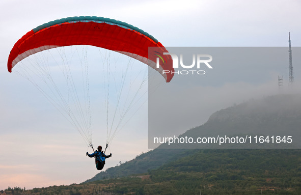 A paraglider flies in the air at a cloud-deep flight camp in Zaozhuang, China, on October 6, 2024. 