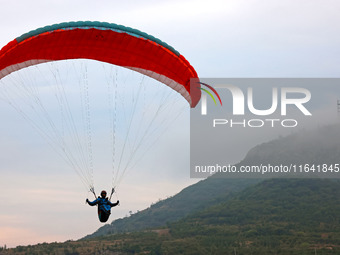 A paraglider flies in the air at a cloud-deep flight camp in Zaozhuang, China, on October 6, 2024. (