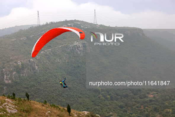 A paraglider flies in the air at a cloud-deep flight camp in Zaozhuang, China, on October 6, 2024. 