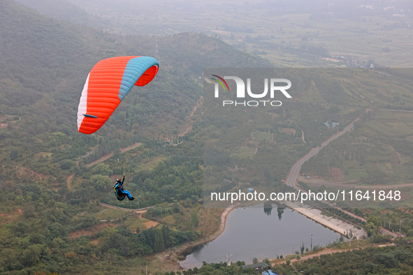 A paraglider flies in the air at a cloud-deep flight camp in Zaozhuang, China, on October 6, 2024. 