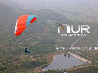 A paraglider flies in the air at a cloud-deep flight camp in Zaozhuang, China, on October 6, 2024. (