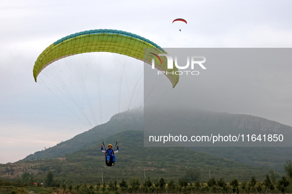 A paraglider flies in the air at a cloud-deep flight camp in Zaozhuang, China, on October 6, 2024. 