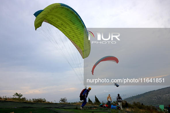 A paraglider flies in the air at a cloud-deep flight camp in Zaozhuang, China, on October 6, 2024. 