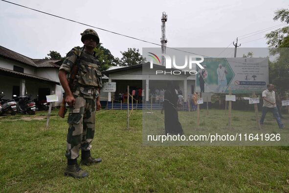 Indian security personnel stand guard as people wait in line to check their names on the draft list at the National Register of Citizens (NR...