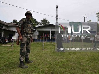 Indian security personnel stand guard as people wait in line to check their names on the draft list at the National Register of Citizens (NR...