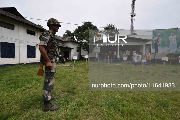 Indian security personnel stand guard as people wait in line to check their names on the draft list at the National Register of Citizens (NR...