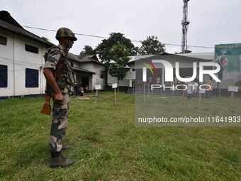 Indian security personnel stand guard as people wait in line to check their names on the draft list at the National Register of Citizens (NR...