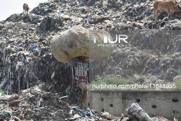 An Indian laborer carries a sack of plastic bottles on his head at a landfill in the Boragaon area of Guwahati, India, on June 4, 2018. 