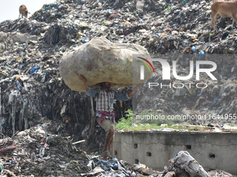 An Indian laborer carries a sack of plastic bottles on his head at a landfill in the Boragaon area of Guwahati, India, on June 4, 2018. (