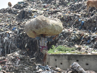 An Indian laborer carries a sack of plastic bottles on his head at a landfill in the Boragaon area of Guwahati, India, on June 4, 2018. (