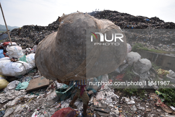 An Indian rag-picker carries a sack with recyclable materials at a landfill in the Boragoan area in Guwahati, India, on June 4, 2018. 