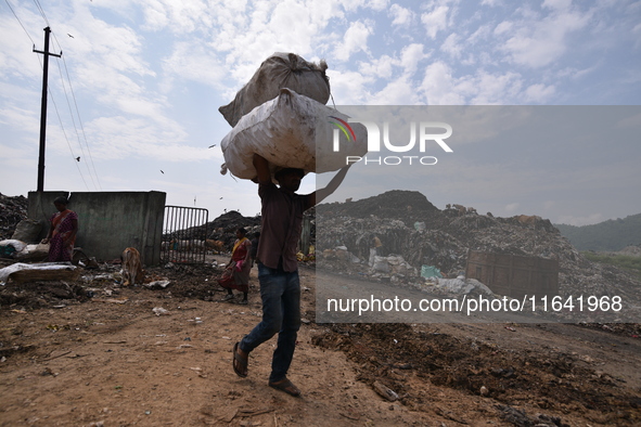 An Indian rag-picker carries a sack with recyclable materials at a landfill in the Boragoan area in Guwahati, India, on June 4, 2018. 