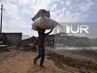 An Indian rag-picker carries a sack with recyclable materials at a landfill in the Boragoan area in Guwahati, India, on June 4, 2018. (