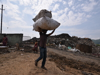 An Indian rag-picker carries a sack with recyclable materials at a landfill in the Boragoan area in Guwahati, India, on June 4, 2018. (