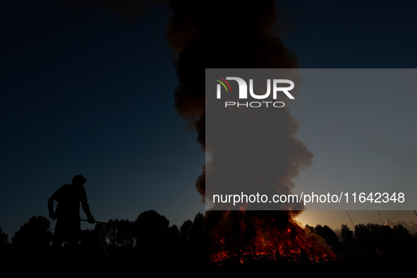 Workers set cables on fire, causing air pollution as they extract copper on the outskirts of Sopore, Jammu and Kashmir, India, on October 6,...