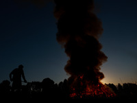 Workers set cables on fire, causing air pollution as they extract copper on the outskirts of Sopore, Jammu and Kashmir, India, on October 6,...