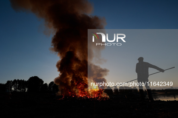 Workers set cables on fire, causing air pollution as they extract copper on the outskirts of Sopore, Jammu and Kashmir, India, on October 6,...