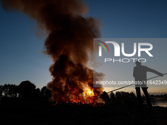 Workers set cables on fire, causing air pollution as they extract copper on the outskirts of Sopore, Jammu and Kashmir, India, on October 6,...