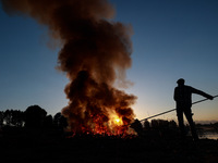 Workers set cables on fire, causing air pollution as they extract copper on the outskirts of Sopore, Jammu and Kashmir, India, on October 6,...