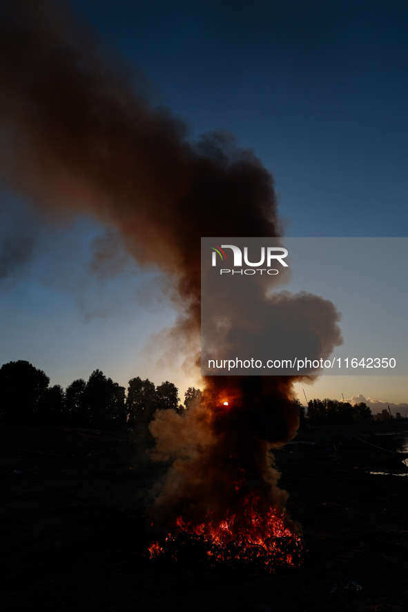 Workers set cables on fire, causing air pollution as they extract copper on the outskirts of Sopore, Jammu and Kashmir, India, on October 6,...