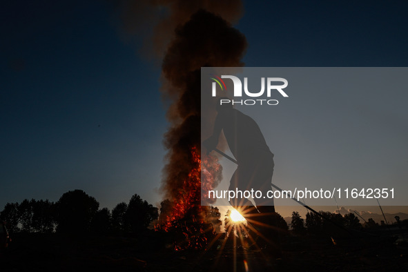 Workers set cables on fire, causing air pollution as they extract copper on the outskirts of Sopore, Jammu and Kashmir, India, on October 6,...