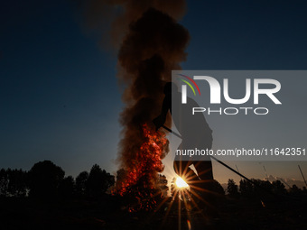 Workers set cables on fire, causing air pollution as they extract copper on the outskirts of Sopore, Jammu and Kashmir, India, on October 6,...