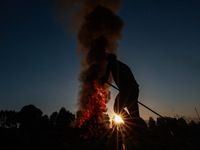 Workers set cables on fire, causing air pollution as they extract copper on the outskirts of Sopore, Jammu and Kashmir, India, on October 6,...