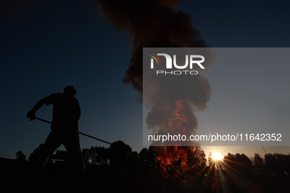 Workers set cables on fire, causing air pollution as they extract copper on the outskirts of Sopore, Jammu and Kashmir, India, on October 6,...