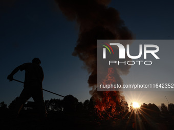 Workers set cables on fire, causing air pollution as they extract copper on the outskirts of Sopore, Jammu and Kashmir, India, on October 6,...