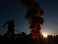 Workers set cables on fire, causing air pollution as they extract copper on the outskirts of Sopore, Jammu and Kashmir, India, on October 6,...