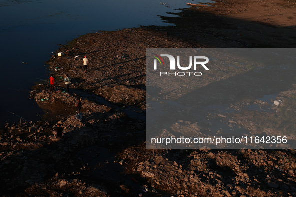 Kashmiri men catch fish on the dried portion of the River Jhelum as the water level of the river decreases in Sopore, Jammu and Kashmir, Ind...