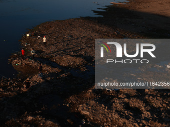 Kashmiri men catch fish on the dried portion of the River Jhelum as the water level of the river decreases in Sopore, Jammu and Kashmir, Ind...