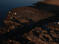 Kashmiri men catch fish on the dried portion of the River Jhelum as the water level of the river decreases in Sopore, Jammu and Kashmir, Ind...