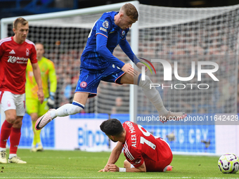 Cole Palmer of Chelsea jumps over Alex Moreno of Nottingham Forest during the Premier League match between Chelsea and Nottingham Forest at...