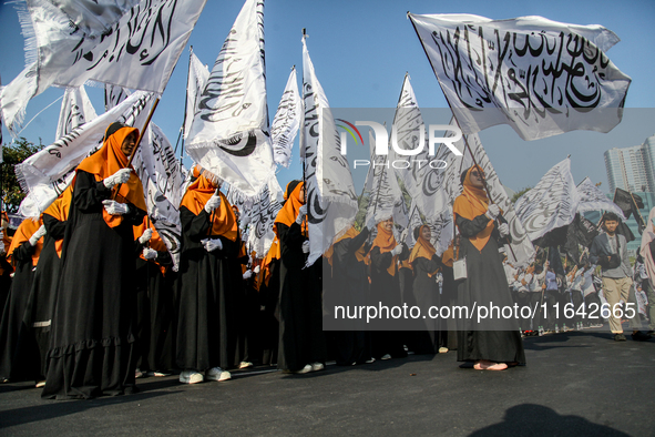 Muslims hold up posters during a pro-Palestinian rally on the eve of the one-year anniversary of the Israel-Hamas conflict in Surabaya, Indo...