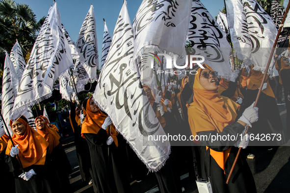 Muslims hold up posters during a pro-Palestinian rally on the eve of the one-year anniversary of the Israel-Hamas conflict in Surabaya, Indo...