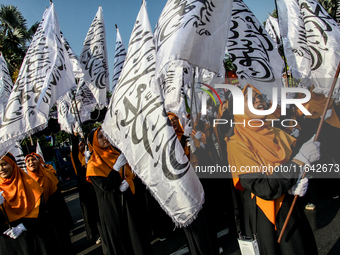 Muslims hold up posters during a pro-Palestinian rally on the eve of the one-year anniversary of the Israel-Hamas conflict in Surabaya, Indo...