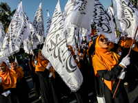 Muslims hold up posters during a pro-Palestinian rally on the eve of the one-year anniversary of the Israel-Hamas conflict in Surabaya, Indo...