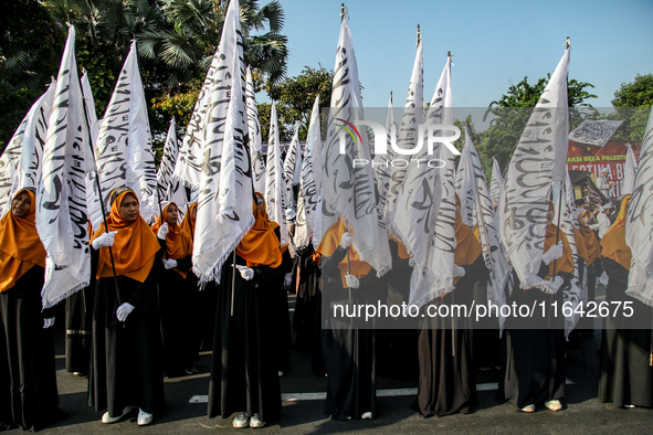 Muslims hold up posters during a pro-Palestinian rally on the eve of the one-year anniversary of the Israel-Hamas conflict in Surabaya, Indo...