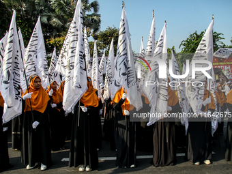 Muslims hold up posters during a pro-Palestinian rally on the eve of the one-year anniversary of the Israel-Hamas conflict in Surabaya, Indo...