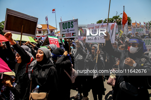 Muslims hold up posters during a pro-Palestinian rally on the eve of the one-year anniversary of the Israel-Hamas conflict in Surabaya, Indo...