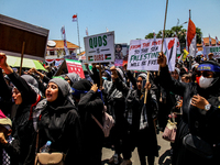 Muslims hold up posters during a pro-Palestinian rally on the eve of the one-year anniversary of the Israel-Hamas conflict in Surabaya, Indo...