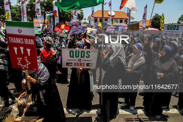 Muslims hold up posters during a pro-Palestinian rally on the eve of the one-year anniversary of the Israel-Hamas conflict in Surabaya, Indo...