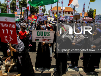 Muslims hold up posters during a pro-Palestinian rally on the eve of the one-year anniversary of the Israel-Hamas conflict in Surabaya, Indo...