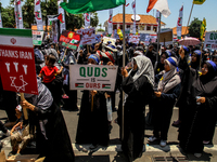 Muslims hold up posters during a pro-Palestinian rally on the eve of the one-year anniversary of the Israel-Hamas conflict in Surabaya, Indo...