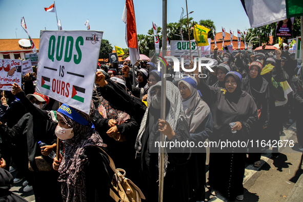 Muslims hold up posters during a pro-Palestinian rally on the eve of the one-year anniversary of the Israel-Hamas conflict in Surabaya, Indo...