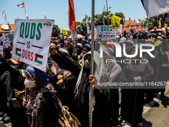 Muslims hold up posters during a pro-Palestinian rally on the eve of the one-year anniversary of the Israel-Hamas conflict in Surabaya, Indo...