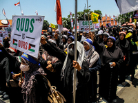 Muslims hold up posters during a pro-Palestinian rally on the eve of the one-year anniversary of the Israel-Hamas conflict in Surabaya, Indo...