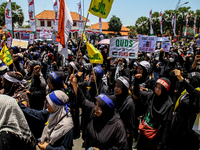 Muslims hold up posters during a pro-Palestinian rally on the eve of the one-year anniversary of the Israel-Hamas conflict in Surabaya, Indo...