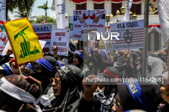 Muslims hold up posters during a pro-Palestinian rally on the eve of the one-year anniversary of the Israel-Hamas conflict in Surabaya, Indo...